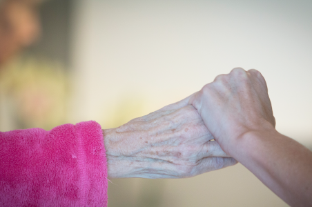 Ældre kvindehånd holder yngre hånd